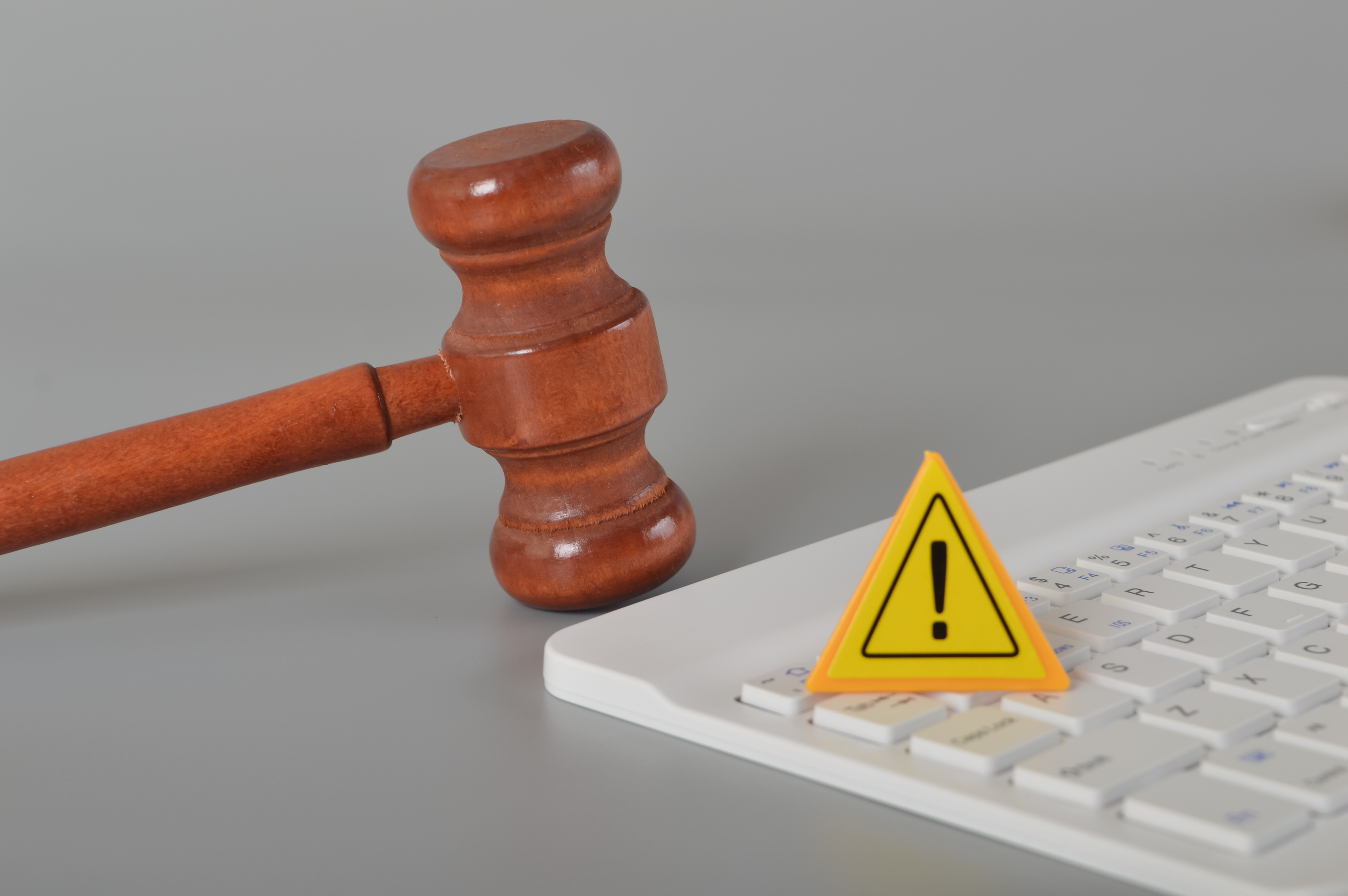 Martelo de juiz ao lado de teclado e sinal de alerta, representando fiscalização e reclamações contra sites de apostas online.