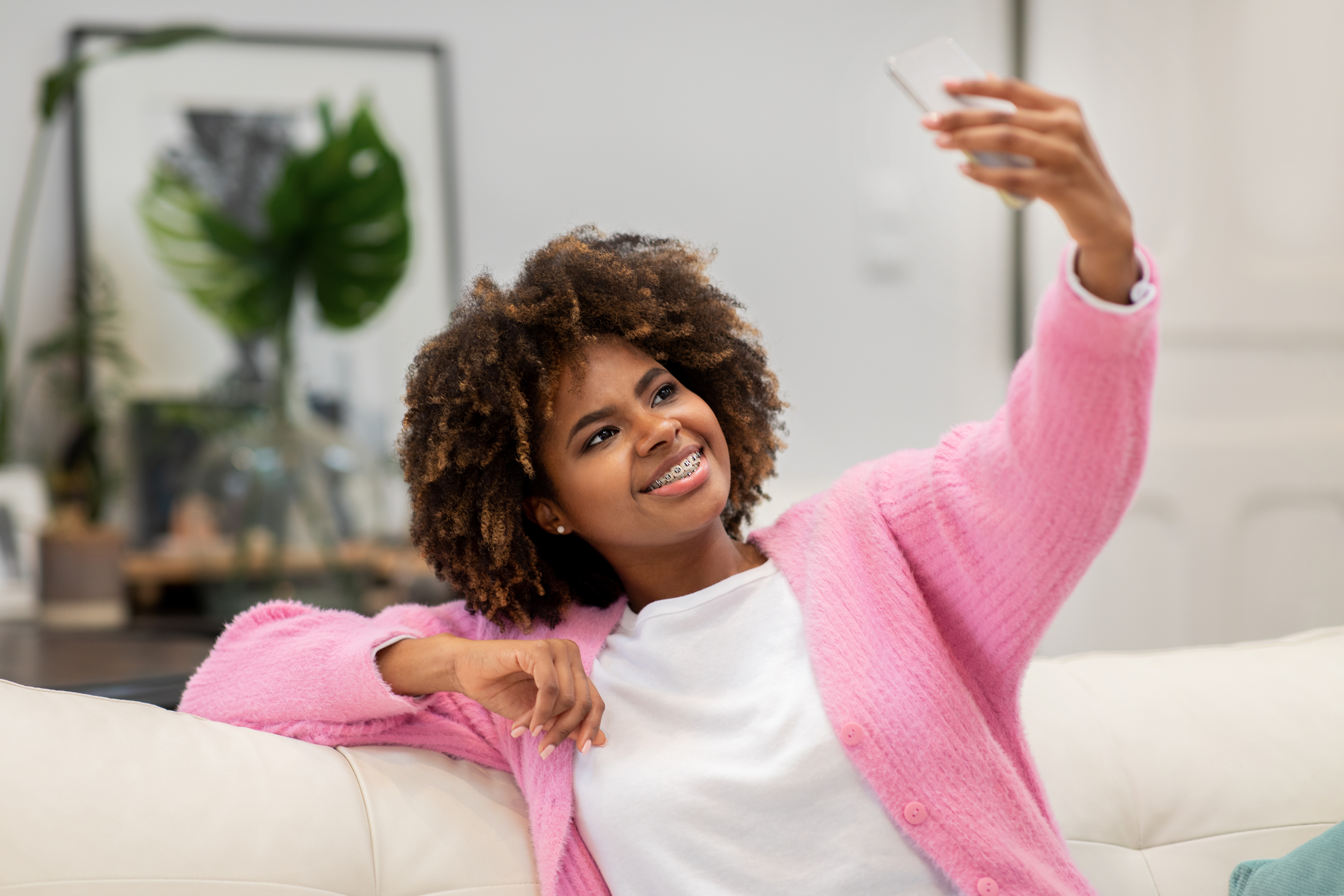 Mulher negra millennial usando o celular em casa para tirar selfie KYC e verificar conta em site de apostas