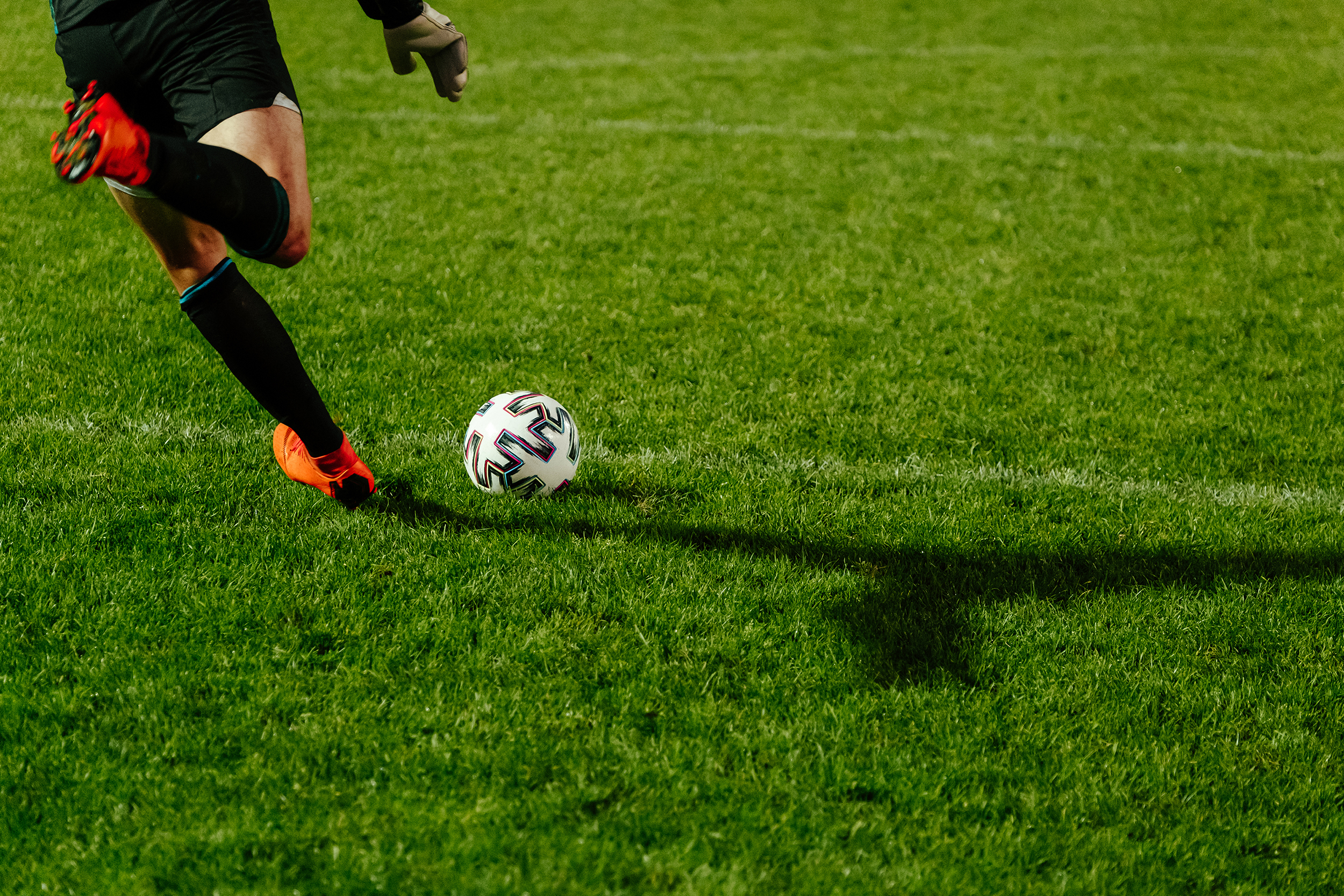 Homem chutando uma bola de futebol em estádio, representando palpites futebol hoje com odds da Libertadores